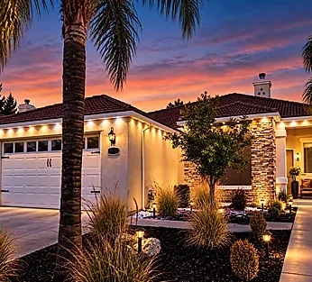 A home with warm white roofline lights and landscaping.