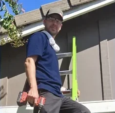 Eric Nordhoff on a ladder installing lights, holding a drill.